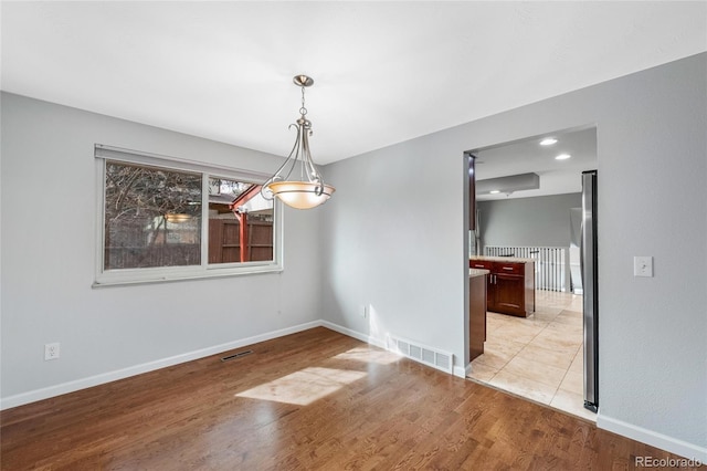 unfurnished dining area with baseboards, light wood-style flooring, and visible vents