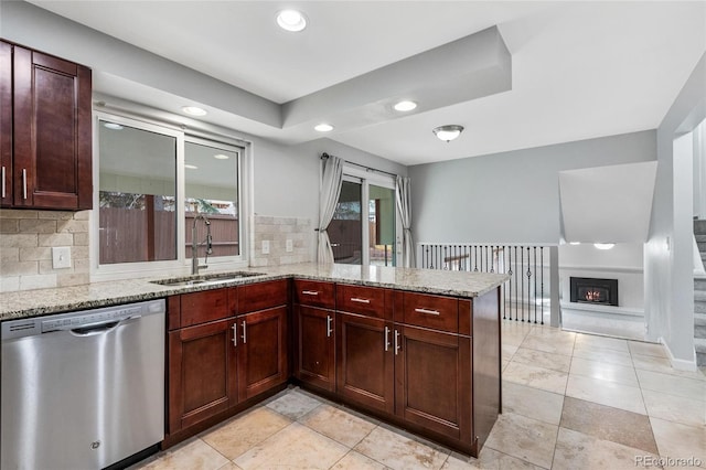 kitchen featuring recessed lighting, dishwasher, light stone counters, and a sink