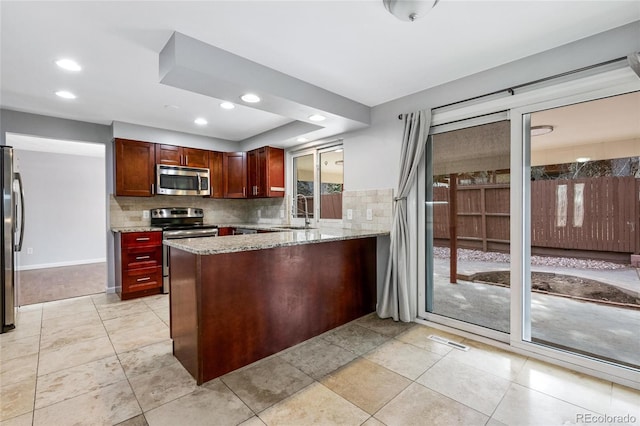 kitchen featuring visible vents, a sink, a peninsula, backsplash, and stainless steel appliances