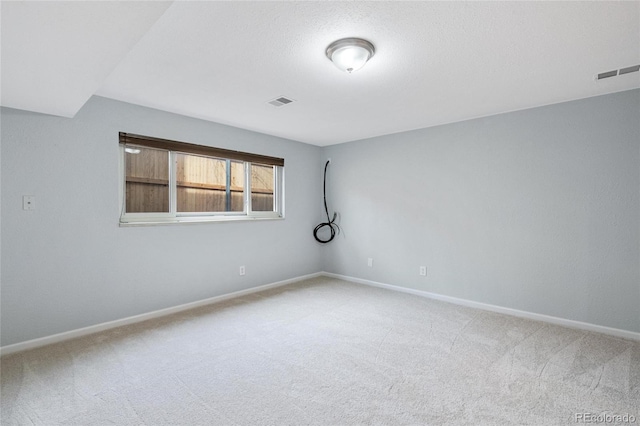 unfurnished room with carpet, visible vents, and baseboards