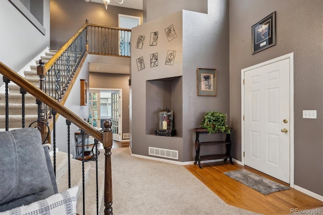 foyer featuring stairs, baseboards, visible vents, and a towering ceiling
