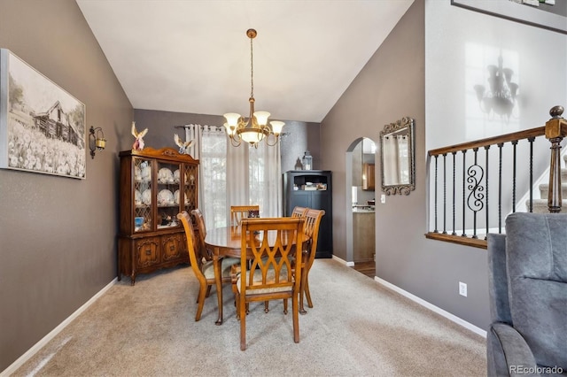 carpeted dining room featuring stairs, baseboards, arched walkways, a notable chandelier, and vaulted ceiling