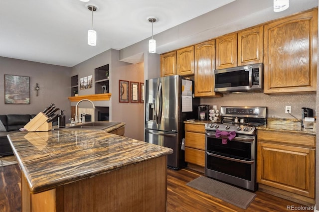 kitchen featuring dark wood-style floors, brown cabinets, a sink, hanging light fixtures, and stainless steel appliances