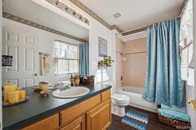 bathroom featuring visible vents, wood finished floors, vanity, toilet, and shower / bathtub combination with curtain