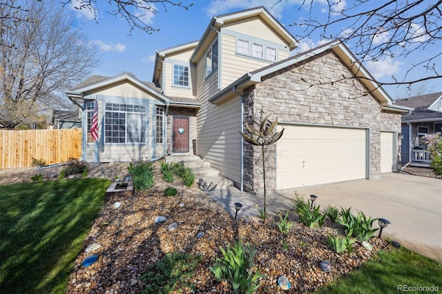traditional home featuring fence, a front lawn, concrete driveway, an attached garage, and stone siding