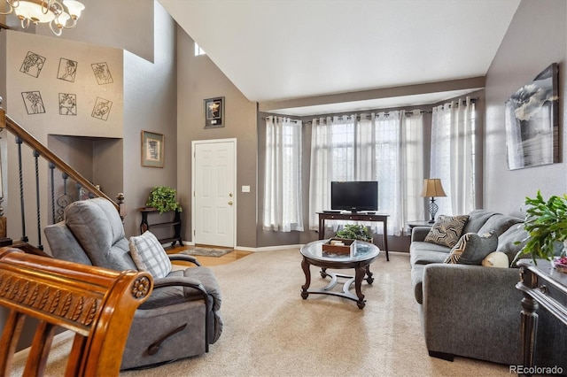 carpeted living area with baseboards, a chandelier, stairway, and high vaulted ceiling
