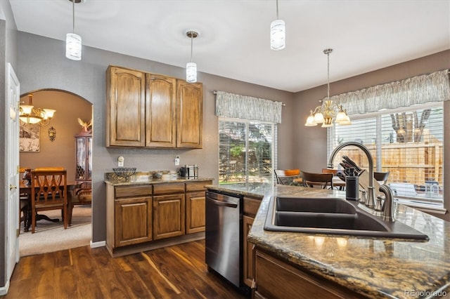 kitchen featuring dark wood-style flooring, an inviting chandelier, a sink, brown cabinetry, and stainless steel dishwasher