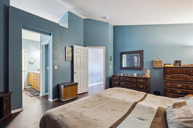 bedroom with baseboards, ensuite bath, high vaulted ceiling, and wood finished floors
