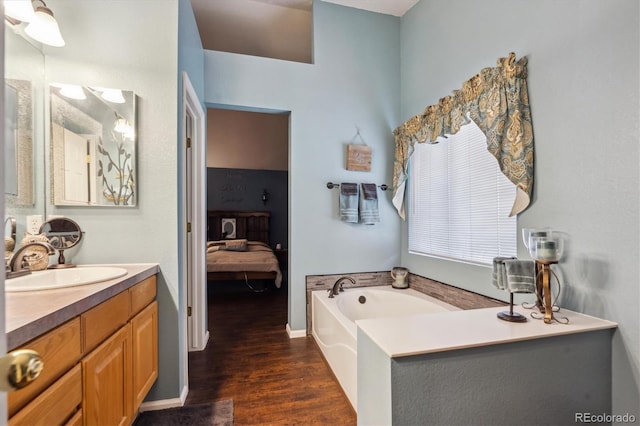 ensuite bathroom with connected bathroom, wood finished floors, a garden tub, and vanity