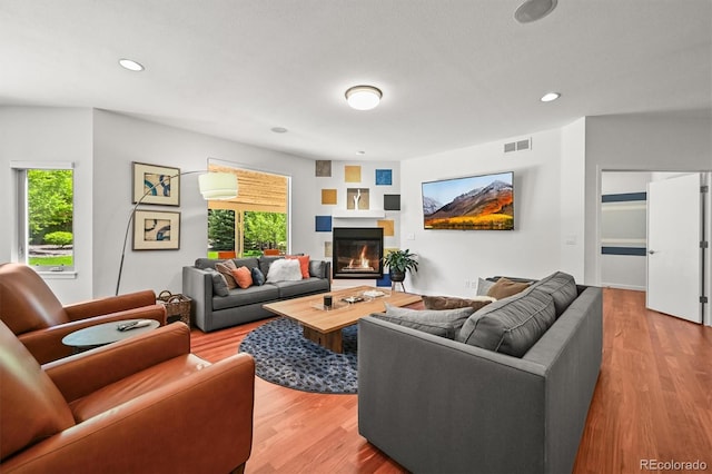living room featuring wood finished floors, a glass covered fireplace, and recessed lighting