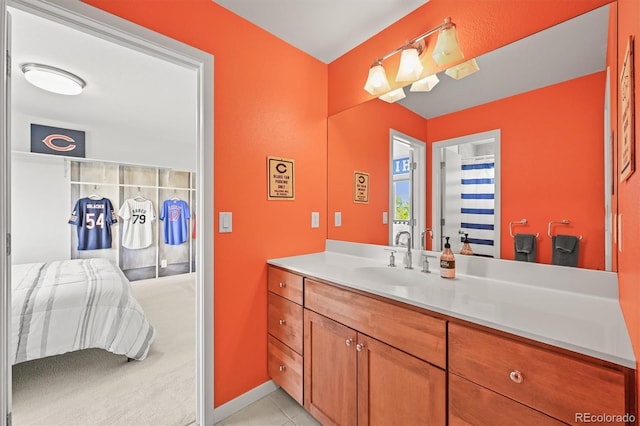 ensuite bathroom with vanity, tile patterned flooring, and baseboards