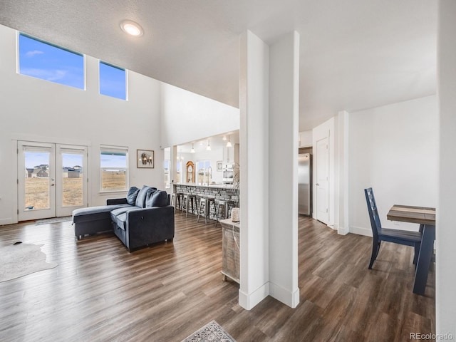 living room with a textured ceiling, dark hardwood / wood-style flooring, and a high ceiling