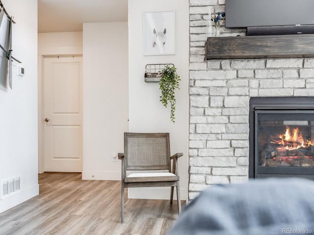 living area featuring light wood-type flooring and a brick fireplace