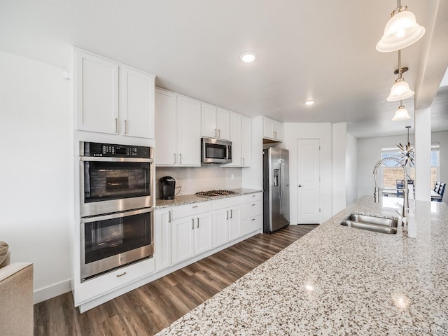 kitchen featuring white cabinets, appliances with stainless steel finishes, dark hardwood / wood-style flooring, and pendant lighting