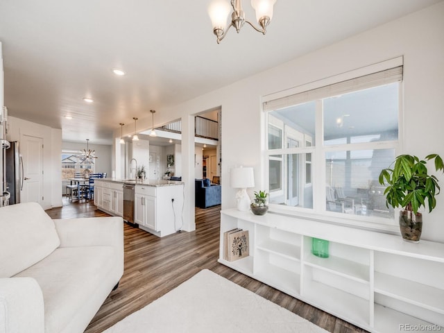 living room with plenty of natural light, a chandelier, dark hardwood / wood-style floors, and sink