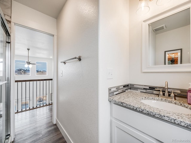 bathroom with hardwood / wood-style flooring, ceiling fan, and vanity