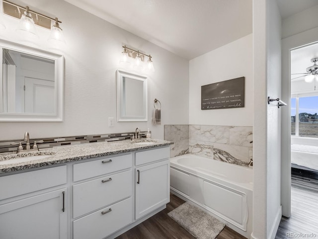 bathroom featuring hardwood / wood-style flooring, vanity, ceiling fan, and a washtub