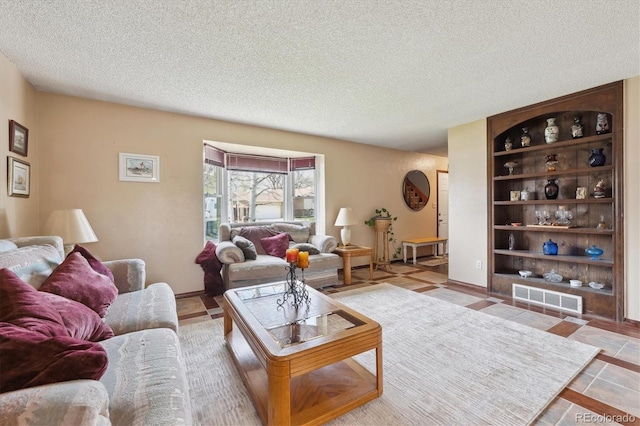 tiled living room with a textured ceiling, visible vents, and built in shelves