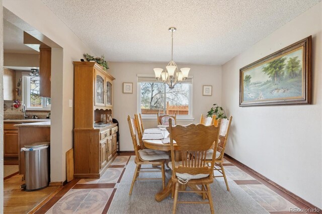 dining space with an inviting chandelier, a healthy amount of sunlight, and a textured ceiling