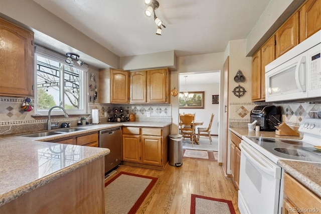 kitchen with a sink, light wood-style floors, white appliances, light countertops, and backsplash