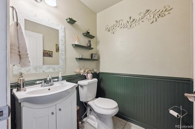 bathroom featuring wainscoting, tile patterned floors, vanity, and toilet