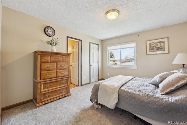 bedroom with a closet, baseboards, a textured ceiling, and light colored carpet