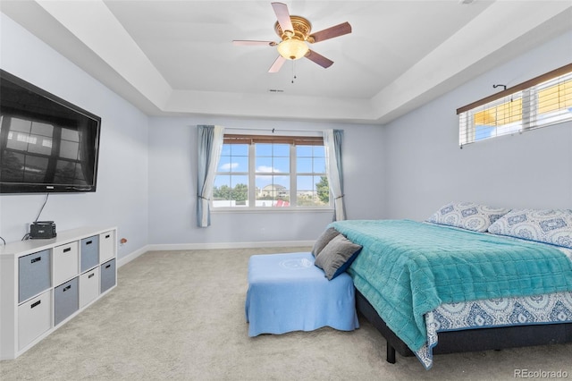 carpeted bedroom with ceiling fan and a raised ceiling