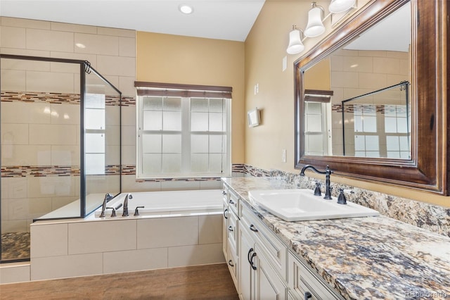 bathroom featuring vanity, hardwood / wood-style flooring, and plus walk in shower