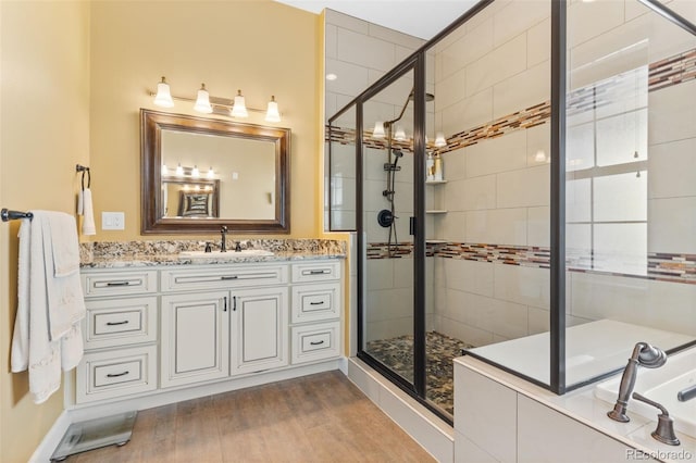 bathroom with vanity, a shower with shower door, tile walls, and wood-type flooring