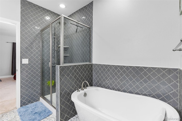 bathroom featuring tile walls and independent shower and bath