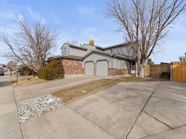 view of side of property featuring driveway, brick siding, an attached garage, and fence