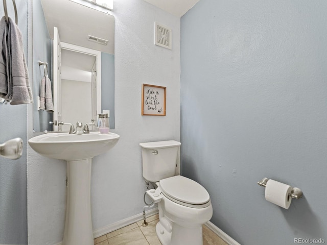 half bath with toilet, tile patterned flooring, visible vents, and baseboards