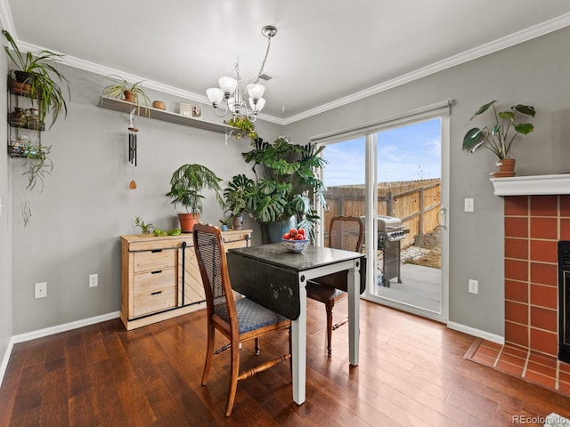 dining space featuring wood finished floors, an inviting chandelier, baseboards, a tiled fireplace, and crown molding