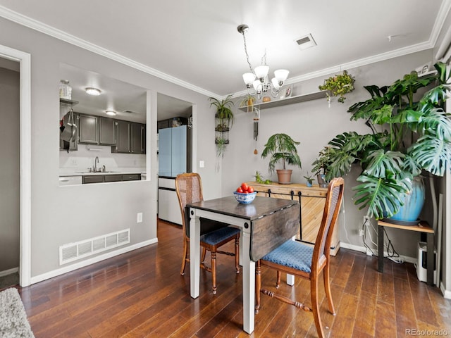 dining room featuring ornamental molding, hardwood / wood-style flooring, visible vents, and a notable chandelier