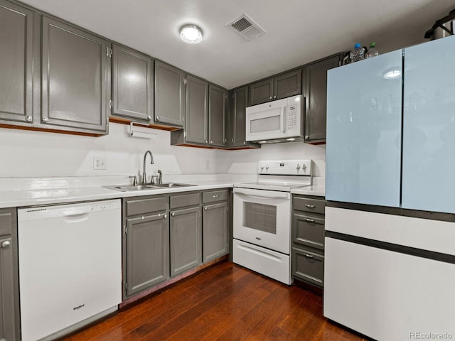 kitchen with dark wood finished floors, light countertops, visible vents, a sink, and white appliances