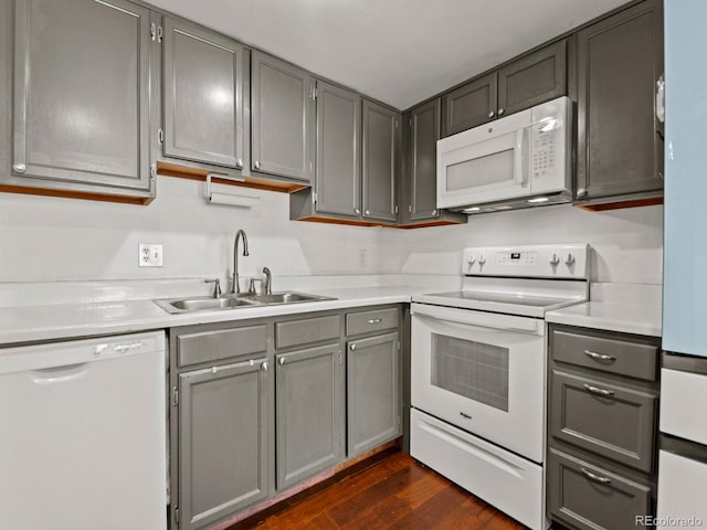 kitchen with white appliances, a sink, and gray cabinetry