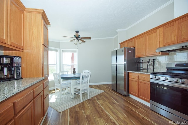 kitchen featuring light stone countertops, dark hardwood / wood-style flooring, ornamental molding, stainless steel appliances, and exhaust hood