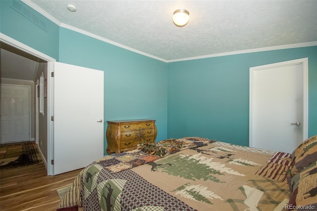 bedroom with hardwood / wood-style floors, a textured ceiling, and ornamental molding