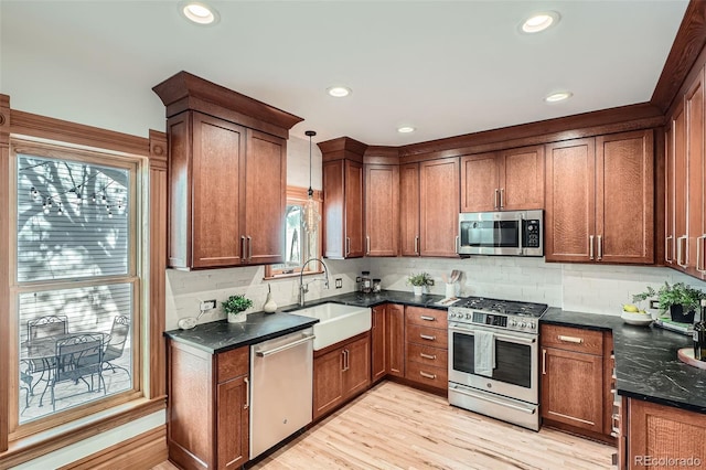 209 S Lincoln St, Denver, CO 80209 - kitchen featuring appliances with stainless steel finishes, a sink, decorative backsplash, light wood-style floors, and dark stone counters