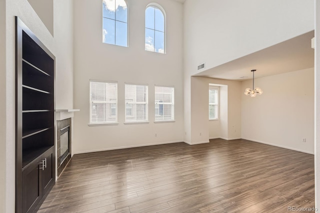 3491 Cascina Pl Unit D, Highlands Ranch, CO 80126 - unfurnished living room featuring a chandelier, a glass covered fireplace, dark wood-style floors, and a high ceiling