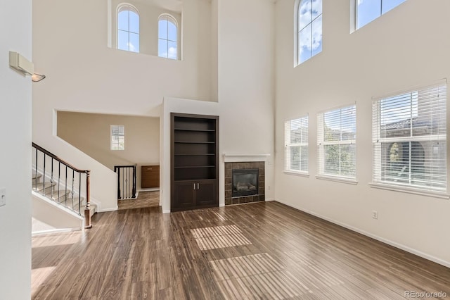 3491 Cascina Pl Unit D, Highlands Ranch, CO 80126 - unfurnished living room featuring a high ceiling, built in shelves, healthy amount of natural light, stairs, and wood finished floors