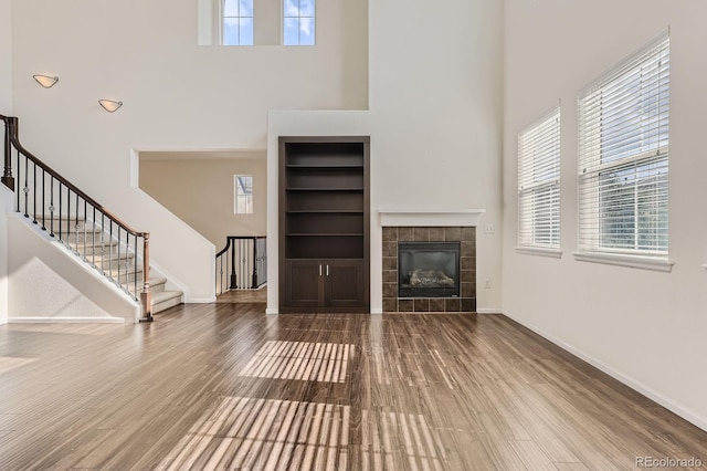 3491 Cascina Pl Unit D, Highlands Ranch, CO 80126 - unfurnished living room featuring built in shelves, healthy amount of natural light, wood finished floors, and a towering ceiling