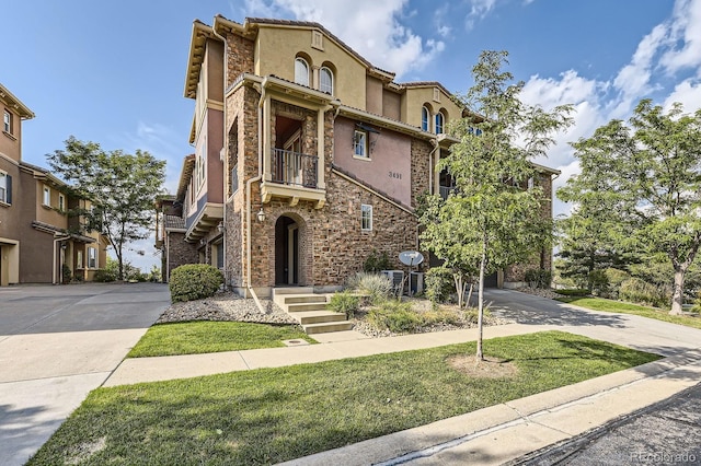3491 Cascina Pl Unit D, Highlands Ranch, CO 80126 - mediterranean / spanish home featuring stone siding, a balcony, concrete driveway, and stucco siding