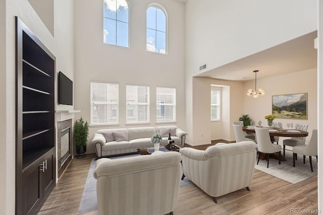 3491 Cascina Pl Unit D, Highlands Ranch, CO 80126 - living room with light wood-type flooring, a glass covered fireplace, a towering ceiling, and a chandelier