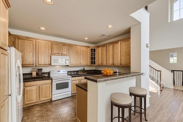 3491 Cascina Pl Unit D, Highlands Ranch, CO 80126 - kitchen with white appliances, a kitchen bar, tile counters, glass insert cabinets, and recessed lighting