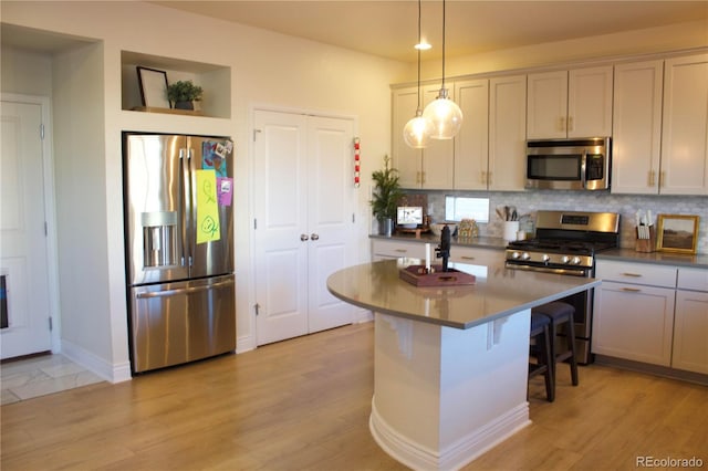 kitchen with pendant lighting, a breakfast bar area, light hardwood / wood-style floors, and appliances with stainless steel finishes