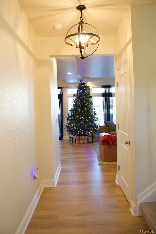 hallway featuring hardwood / wood-style flooring and a notable chandelier