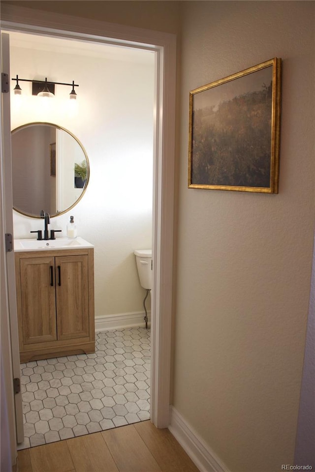 bathroom featuring vanity, wood-type flooring, and toilet