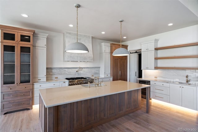 kitchen featuring light hardwood / wood-style floors, white cabinets, a kitchen island with sink, and hanging light fixtures