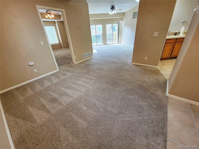 spare room featuring light carpet, sink, and ceiling fan